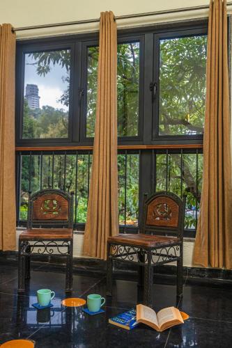 two chairs and a table in front of a window at SaffronStays Amavi Beach House in Dapoli