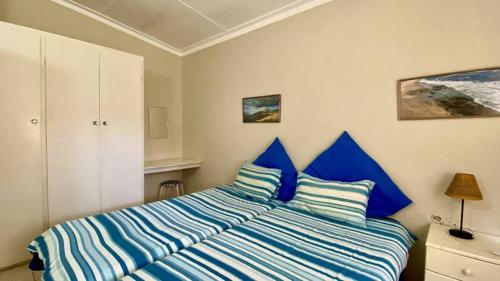 Schlafzimmer mit einem Bett mit blauen und weißen Streifen in der Unterkunft Huis KlipdriftSelf Catering &B&B in Henties Bay