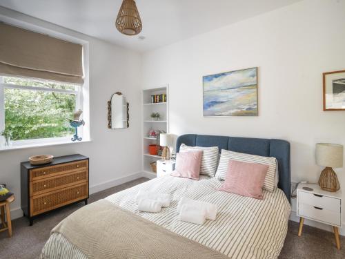 a bedroom with a bed with pink pillows and a window at Seaward in Lyme Regis