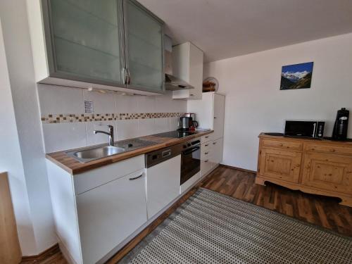 a small kitchen with white cabinets and a sink at Ferienlandhaus Höfer in Fulpmes