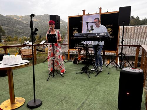a woman standing on a stage with a microphone at Ethnic Grand Room -Tara Place in Mojkovac