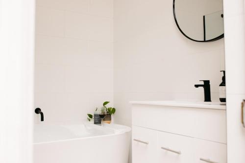 a white bathroom with a sink and a mirror at Luxurious terrace home in heart of town in Bendigo
