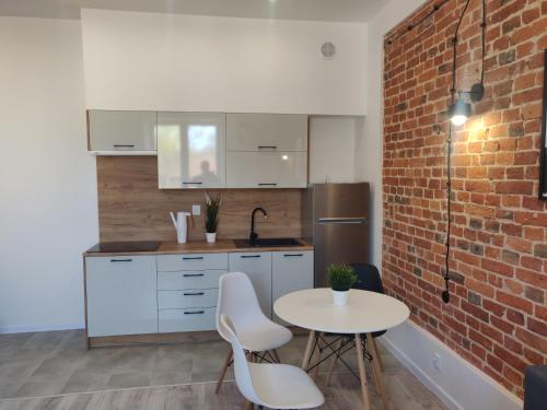 a kitchen with a table and a brick wall at Konopnickiej 9 Apartament Loft dostęp na kod in Pabianice