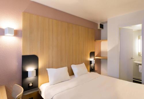 una camera da letto con un grande letto bianco con due cuscini di B&B HOTEL Lorient Lanester a Lanester