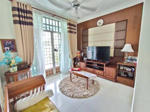 a living room with a couch and a tv and a table at The Bungalow Homestay by Cheta in Alor Setar