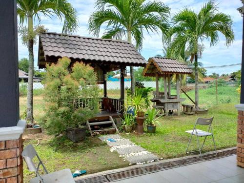 a backyard with a gazebo and chairs and palm trees at The Bungalow Homestay by Cheta in Alor Setar