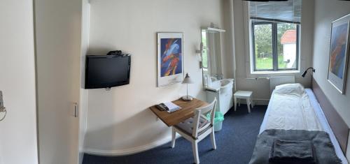een kamer met een bed, een bureau en een televisie bij Hotel Crone in Grenå