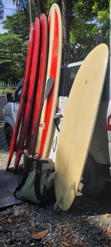 a group of surfboards are leaned up against a car at La Vida Hostel in Puerto Princesa City