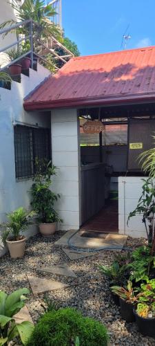 a small house with a red roof and a gate at La Vida Hostel in Puerto Princesa City