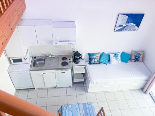 a small white room with a kitchen and a couch at La Morandiere in Grayan-et-lʼHôpital