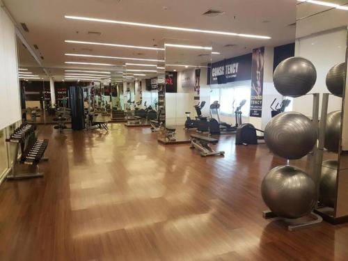 a gym with a wooden floor and exercise equipment at Tanglin Orchard Apartment (2BR) in Surabaya