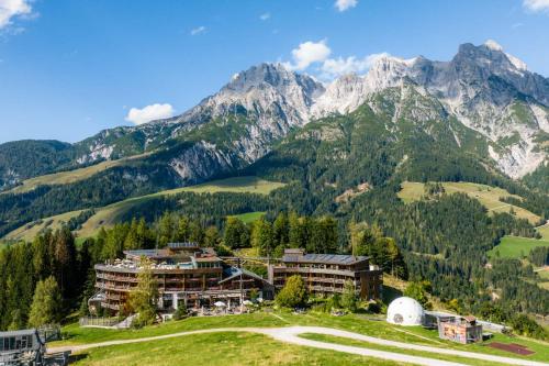 a hotel in the mountains with mountains in the background at Holzhotel Forsthofalm in Leogang