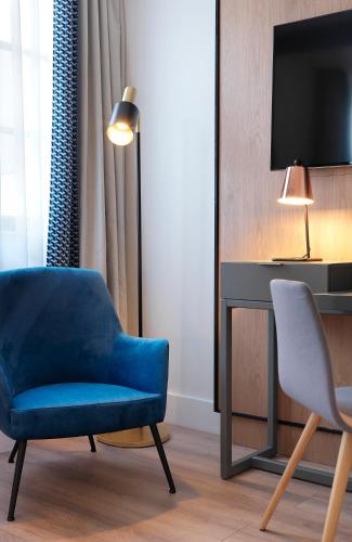 a living room with a blue chair and a tv at Renaissance Paris Vendome Hotel in Paris