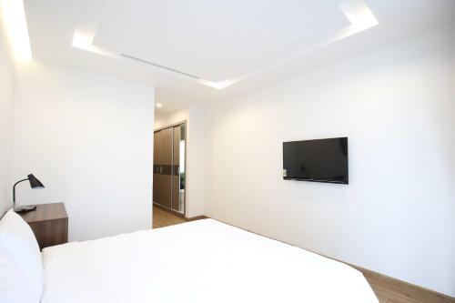 a bedroom with a bed and a tv on the wall at Investland- Vinhomes Metropolis one, two, three, four bedrooms in Hanoi