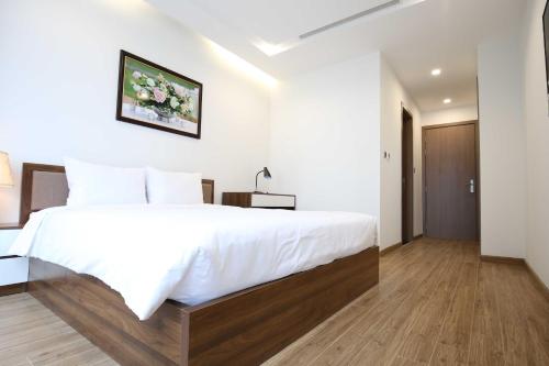 a bedroom with a large white bed and wooden floors at Investland- Vinhomes Metropolis one, two, three, four bedrooms in Hanoi