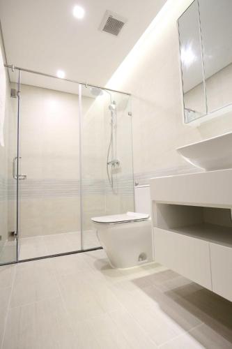 a white bathroom with a glass shower and a toilet at Investland- Vinhomes Metropolis one, two, three, four bedrooms in Hanoi
