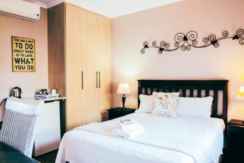 een slaapkamer met een groot wit bed en een tafel bij Villa Mosaiko in Kathu