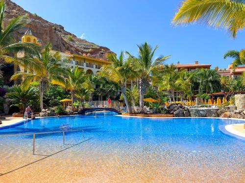 a large swimming pool in a resort with palm trees at Cordial Mogán Solaz in Puerto de Mogán