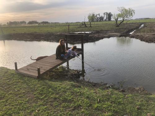 a woman and a child sitting on a dock in the water at Estancia Pedro Chico - Hotel Rural in Chascomús