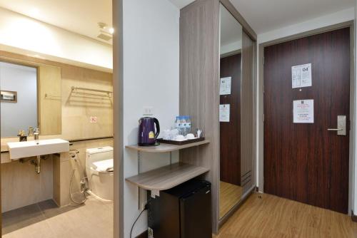 een badkamer met een wastafel, een toilet en een spiegel bij Bedever Boutique Bangkok Hotel - BTS Phra Khanong in Bangkok