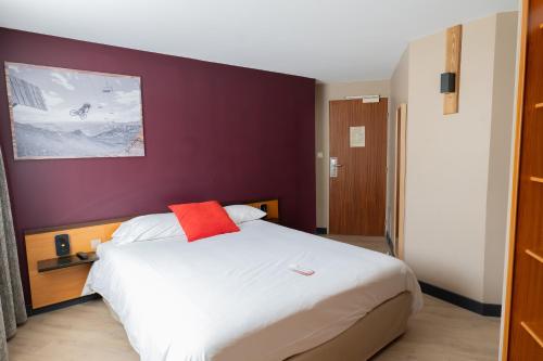 een slaapkamer met een wit bed en een rood kussen bij Hôtel Les Arches in Saint-Lary-Soulan