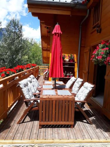 a wooden deck with two chairs and an umbrella at Séjour en famille dans un chalet cosy! in Briançon