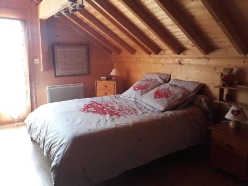 a bedroom with a white bed with red flowers on it at Séjour en famille dans un chalet cosy! in Briançon