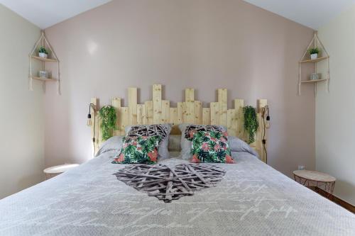 Schlafzimmer mit einem großen Bett mit einem Kopfteil aus Holz in der Unterkunft La Petite Maison Du Montjard 