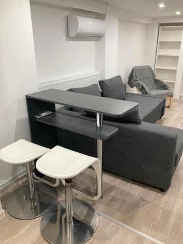 a table and two stools in a living room with a couch at Dobozi Apartman in Debrecen