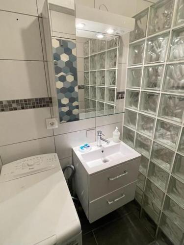 une salle de bain blanche avec un lavabo et un miroir dans l'établissement Studio Cozy avec Terrasse en centre ville !, à Roissy-en-Brie