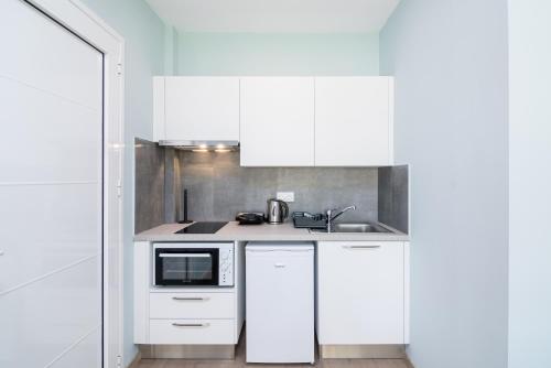 a white kitchen with a sink and a microwave at Helion Apartments in Gouvia