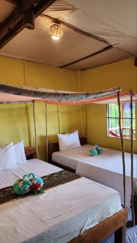 two beds in a room with yellow walls at Kohrong Sea Views Bungalows in Koh Rong Island