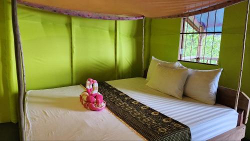 a bed in a room with a green wall at Kohrong Sea Views Bungalows in Koh Rong Island