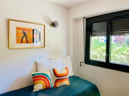 um quarto com uma cama com uma janela e 2 almofadas em CAVALOC.FR STUDIO RETRORANGE em Cavalaire-sur-Mer