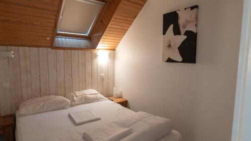 een slaapkamer met een bed met witte lakens en een raam bij Résidence Les Arches in Saint-Lary-Soulan