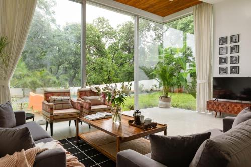 a living room filled with furniture and a large window at La Meira 3BHK Villas in Assagao with Private Pool, Garden, Caretaker, Kitchen & Security in Vagator