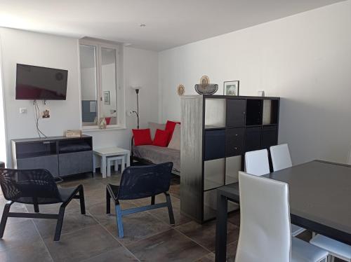 un salon avec une table, des chaises et une télévision dans l'établissement La halte du Clos, à Souvigny