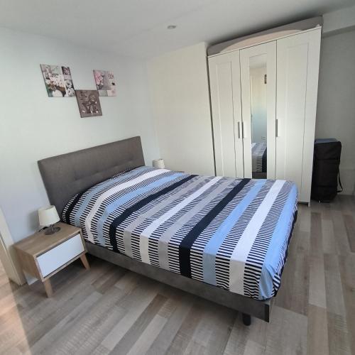 - une chambre avec un lit avec une couette à rayures et une table dans l'établissement Le Cocon de Tom, à Colmar