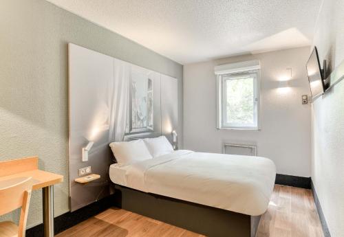 サン・ジャン・ド・ヴェダにあるB&B HOTEL Montpellier 1のベッドとテーブルが備わるホテルルームです。