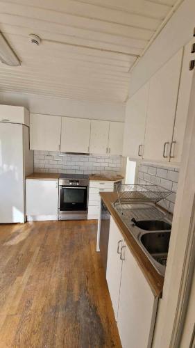 uma pequena cozinha com armários brancos e um lavatório em Home Express em Asker