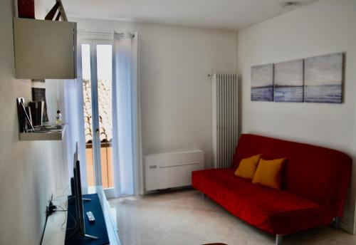 ein Wohnzimmer mit einem roten Sofa und einem TV in der Unterkunft Garibaldi18 in Desenzano del Garda