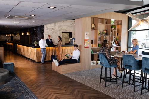 a lobby of a restaurant with people sitting at a bar at Mercure Valenciennes Centre in Valenciennes