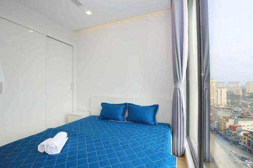 a bedroom with a blue bed and a window at Investland- Vinhomes Metropolis one, two, three, four bedrooms in Hanoi