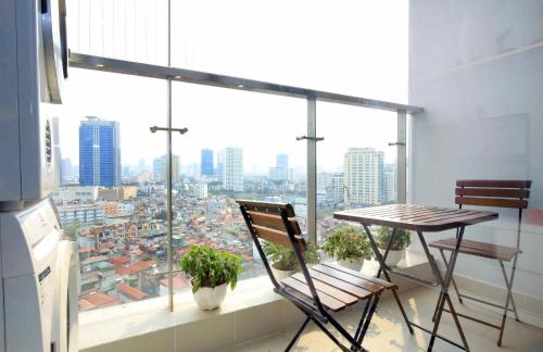 a balcony with a table and chairs in front of a window at Investland- Vinhomes Metropolis one, two, three, four bedrooms in Hanoi