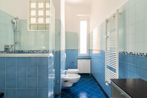 a blue tiled bathroom with a toilet and a sink at santa tecla living faravelli 4 in Milan