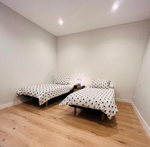 two beds in a room with wooden floors at El Mirador De La Puebla Vut ATUAIRE Parking Incluido in Burgos