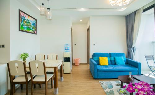 a living room with a table and a blue couch at Investland- Vinhomes Metropolis one, two, three, four bedrooms in Hanoi