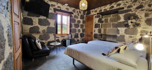 a bedroom with a bed and a chair in a stone wall at El Batan Resort in Santa Brígida