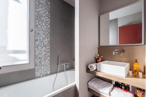 une salle de bain avec une baignoire, un lavabo et un miroir dans l'établissement Veeve - Soulful Fusion, à Paris