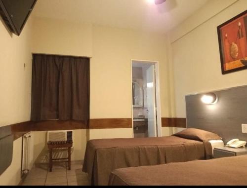a hotel room with two beds and a window at Hotel Nontue Abasto Buenos Aires in Buenos Aires